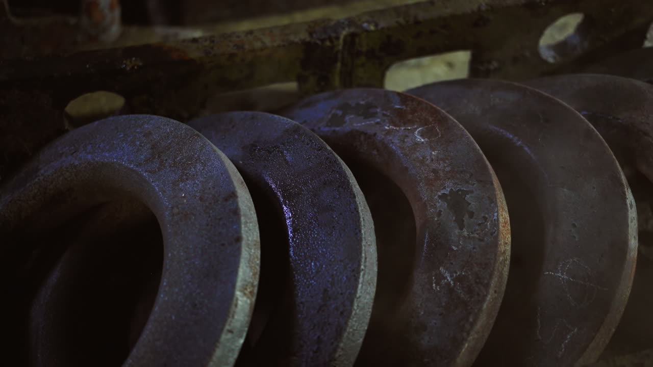 discos metálicos apilados con óxido y pátina que se enfrían con vapor visible en la fundición