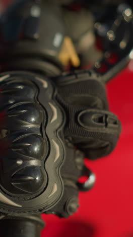 primer plano de la mano de un motociclista usando guantes de protección mientras usa dos dedos para sostener y liberar la palanca de embrague en una motocicleta, un reloj inteligente es visible en la muñeca