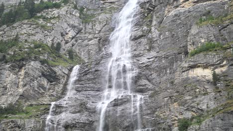 giant waterfall over the rocks falling down on a bright day in lauterbrunnen in switzerland. slow-motion shot.