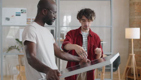 multiethnic male colleagues discussing solar panel in office