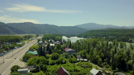 Vuelo-Aéreo-Sobre-La-Carretera-Vista-Del-Río-Turquesa-De-Montaña-También-Visible-Viaducto-De-La-Ciudad-Turística