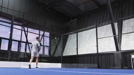young man and woman playing padel tennis on indoor court, enjoying competitive match