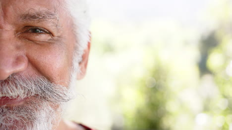 Medio-Retrato-De-Un-Hombre-Birracial-Con-Barba-Blanca-Sonriendo-En-La-Naturaleza-Soleada,-Espacio-Para-Copiar,-Cámara-Lenta