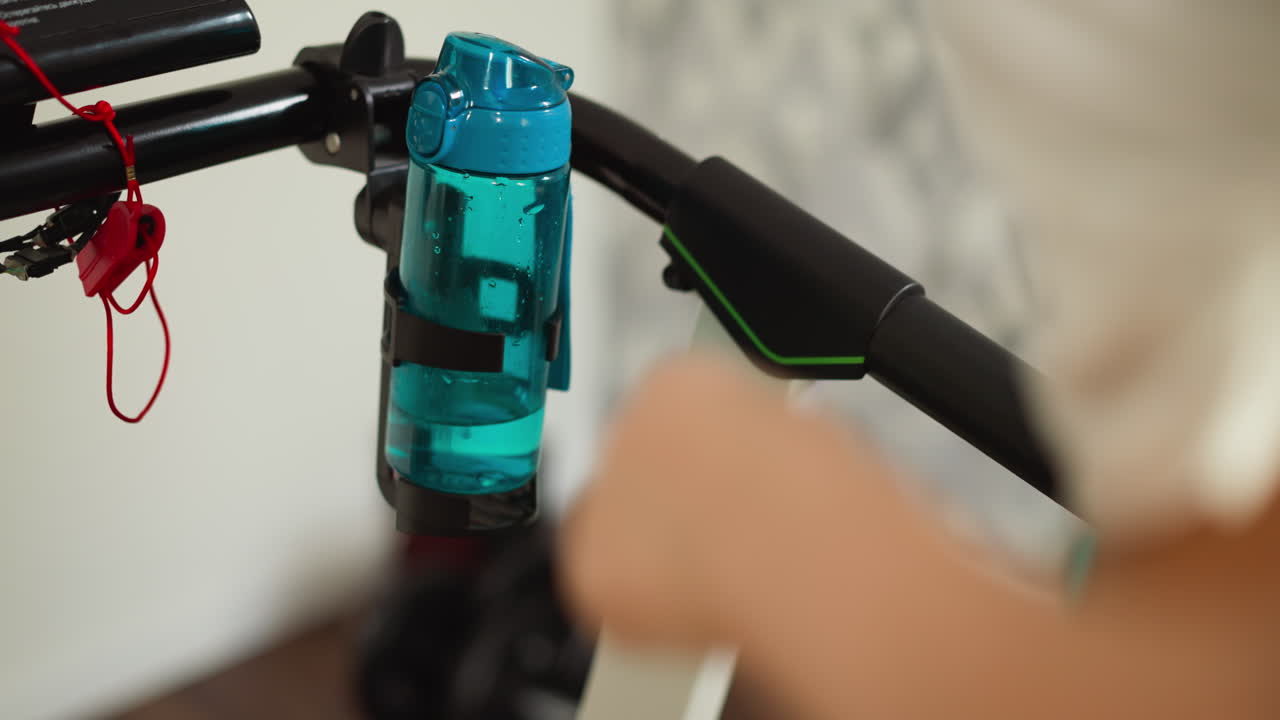 botella de agua en el soporte de la cinta de correr en el hogar de cerca. bebida refrescante para la mujer haciendo ejercicio cardio duro con la máquina en la casa. mantener hidratado haciendo ejercicio