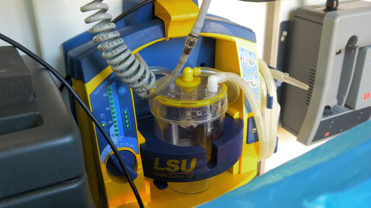 unidad de succión portátil laerdal dentro del vehículo de servicio médico de emergencia, utilizada para la limpieza segura y efectiva de las vías respiratorias del paciente, equipo paramédico, tiro medio de mano