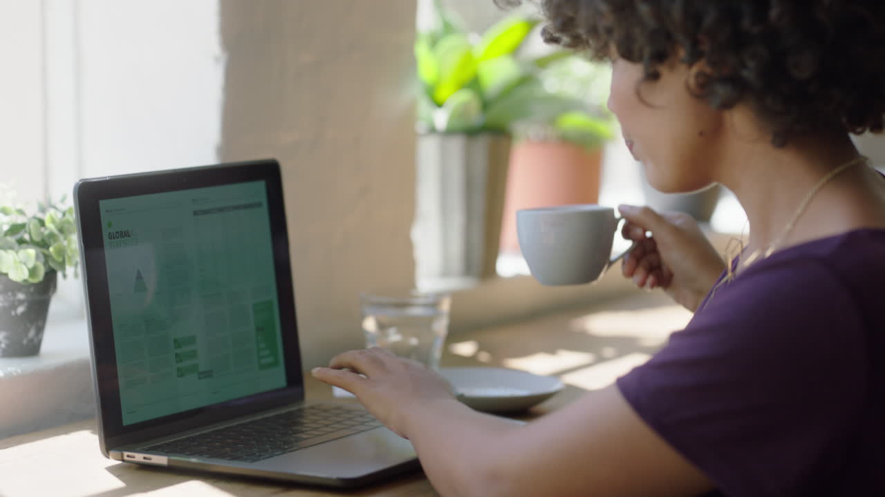 mujer de negocios negra exitosa usando una computadora portátil bebiendo café trabajando en un documento de proyecto corporativo disfrutando de relajarse en casa