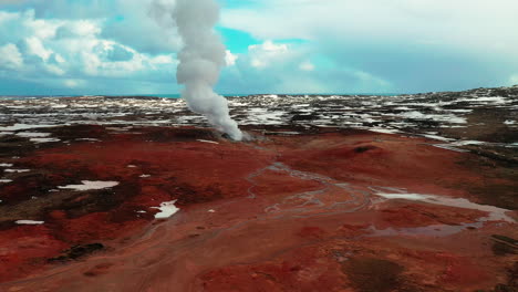 smoke rising from the ground in gunnuhver geothermal area in reykjanes peninsula in iceland with blue sky on the background - aerial drone shot
