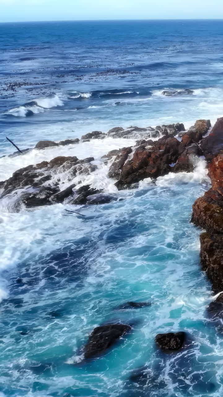 Onde oceaniche potenti che si infrangono contro una costa rocciosa frastagliata
