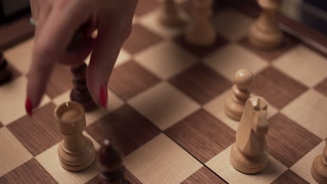 Rook-devouring-a-wooden-chess-pawn,-angled-close-up