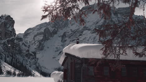 snow covered wooden cabin in sunshine, wintry lake braies, dolomites