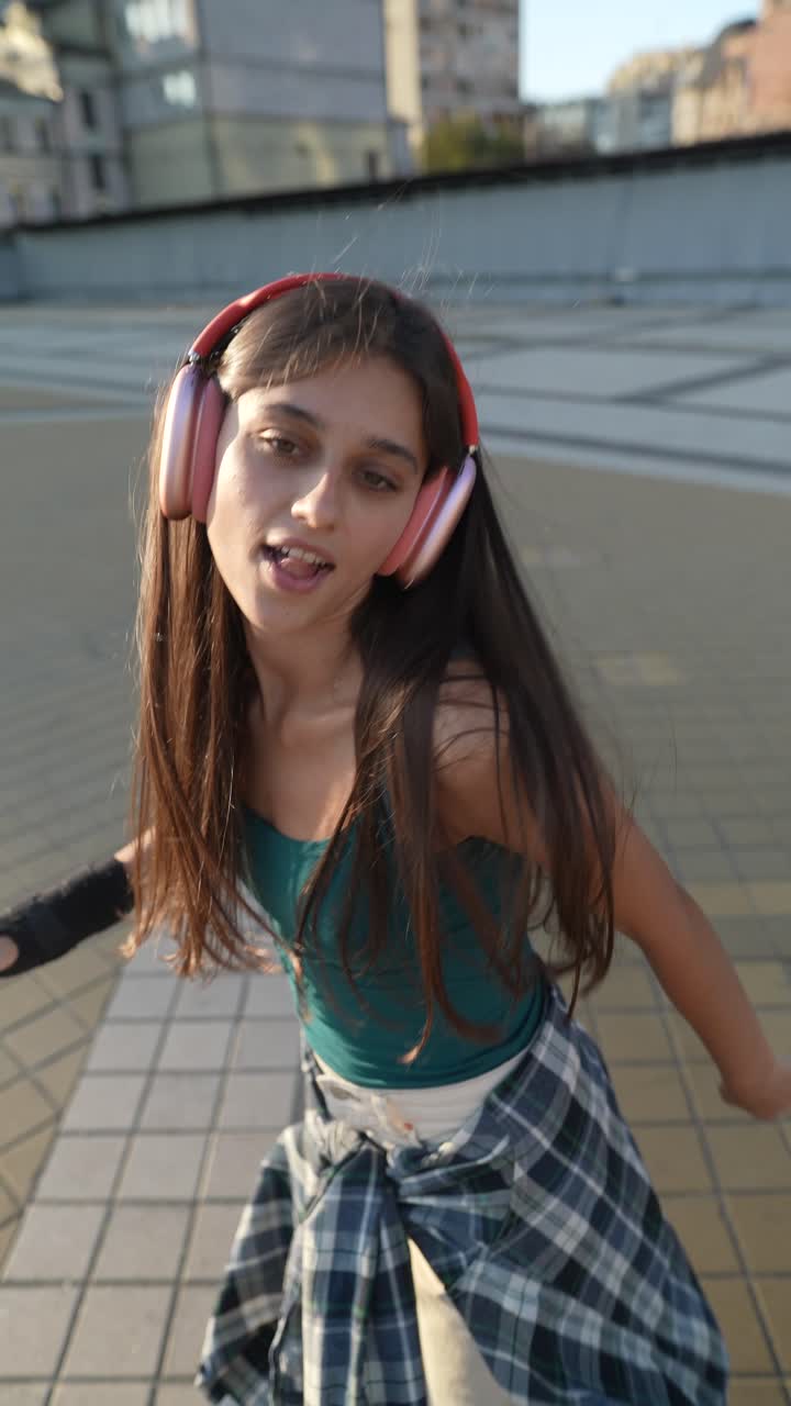 Ragazza adolescente che fa skateboard e ascolta musica in città