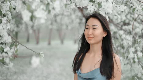 woman in a blue dress among spring blossoms