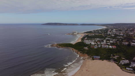 South-Africa-George-Mossel-Bay-Garden-Route-beach-aerial-drone-cinematic-holiday-vacation-town-Jeffreys-Bay-waves-crashing-aqua-blue-brown-ocean-late-morning-afternoon-cloudy-Africa-forward-movement