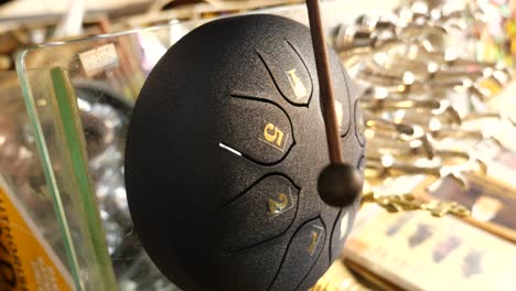 close-up of a black steel tongue drum with golden numbers and a mallet