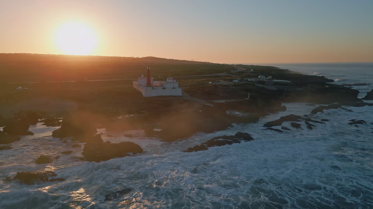 Vista aerea di una maestosa alba sulla costa oceanica. Faro che si erge su una pianura costiera.