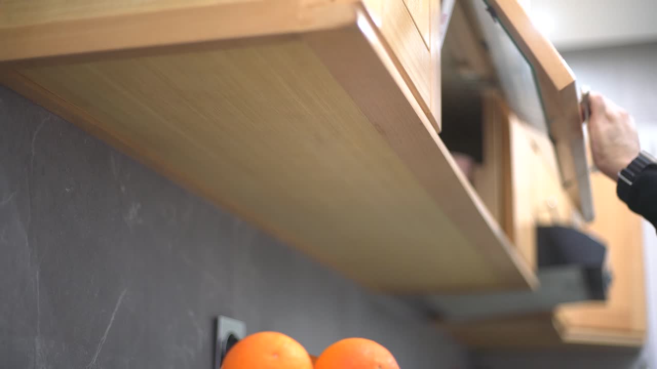 un hombre abre la unidad de la cocina para tomar y volver a poner un stemware