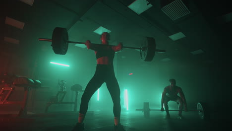 powerlifting training in fitness hall two person are lifting barbells in dark hall physical exercise