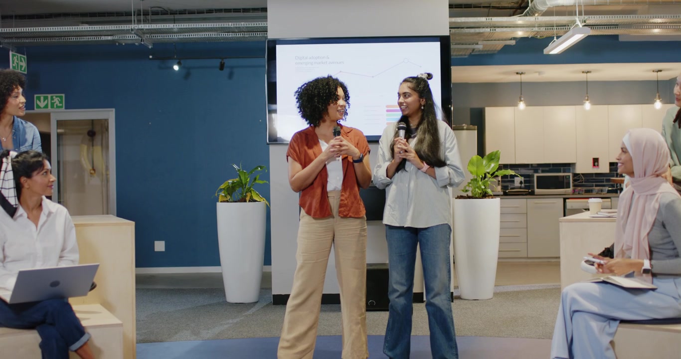 African American and Indian women starting talk presenting charts with mics informing team at work