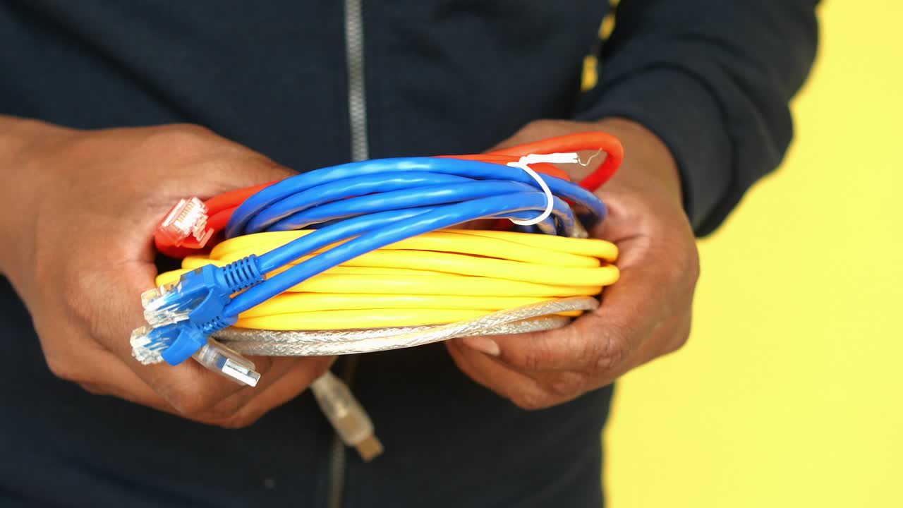 Hands holding various colored network and USB cables