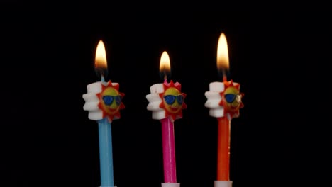 velas festivas de cumpleaños en forma de sol en gafas de sol girando, girando aisladas sobre un fondo negro