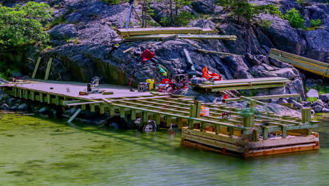 Time-lapse-of-workers-building-a-wharf-at-cliff-by-the-sea,-sunny,-summer-day