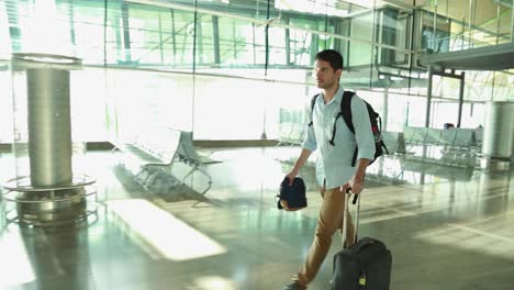 male traveler walking in an empty airport with backpack and carry-on