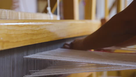 a women's hands using a loom to create a tapestry