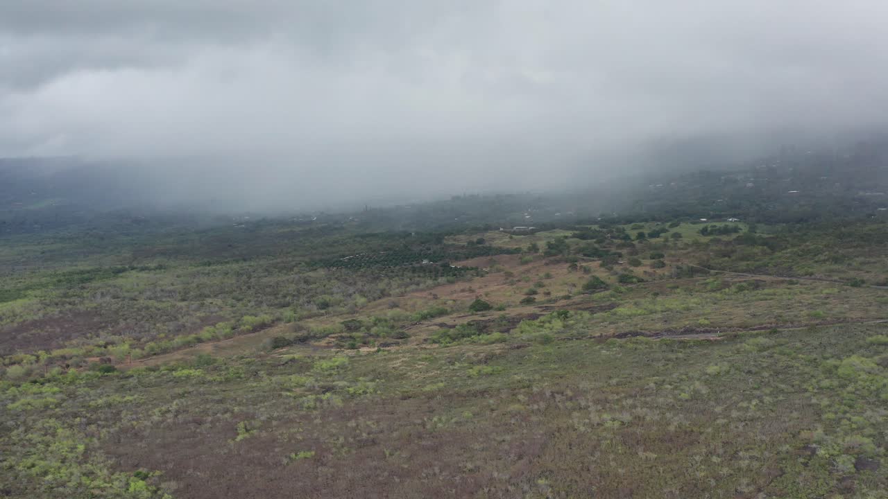 Wide aerial panning shot of the active volcano Hualālai, as it disappears into the clouds on the Big Island of Hawai'i