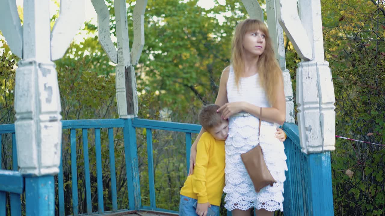 젊은 어머니는 서 있는 아들을 안아주고 있습니다.