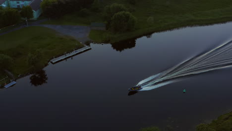 Aerial-tracking-follows-inflatable-boat-with-large-wake-driving-along-calm-river-water