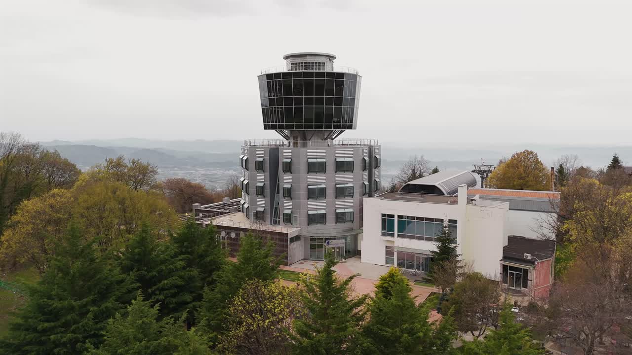 Drone view of modern building amid lush trees in Albania's Tirana