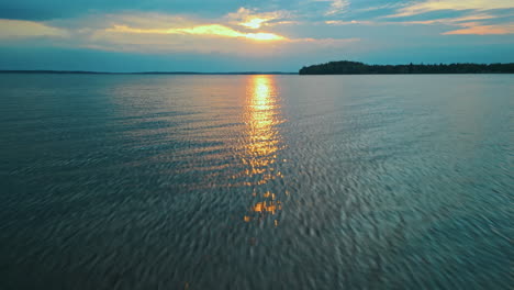 paisaje lacustre en el sur de finlandia, puesta de sol que se refleja en el agua, inclinándose hacia arriba y revelando el paisaje con lago, bosque, ciudad y puesta de sol