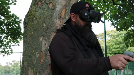 bearded male wearing wireless fpv goggles controlling drone in park with motion joystick