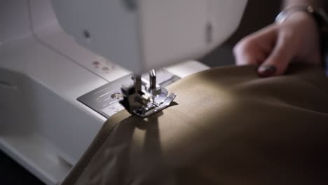 sewing machine operated by hands of female with colored nails, close up view