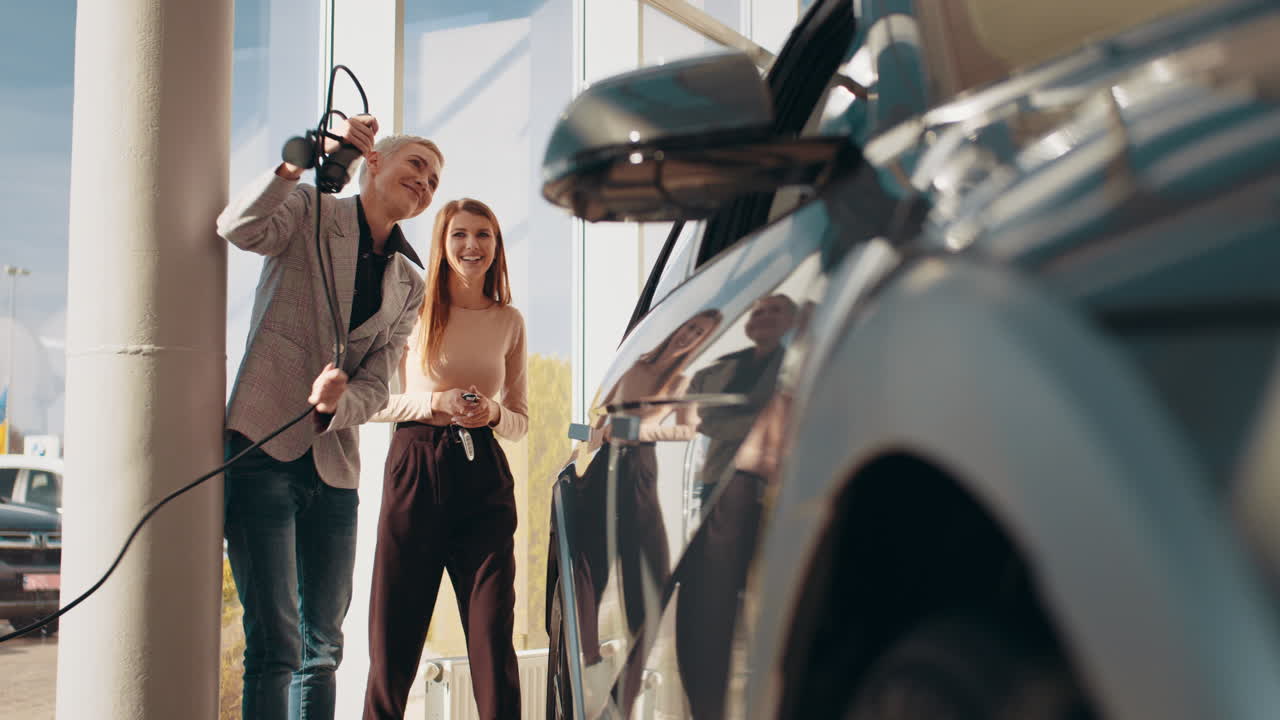 mujeres mirando un coche eléctrico en una sala de exposiciones