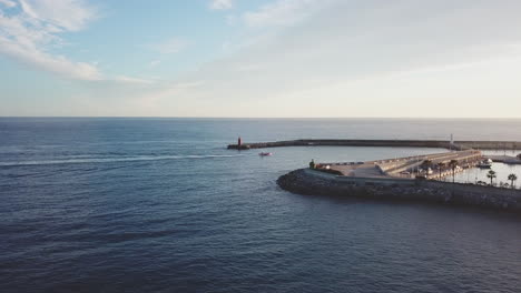 Fisher-boat-entering-port-harbor-and-lighthouse-in-pier-aerial-view