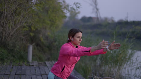 woman performing squats outdoors by the water