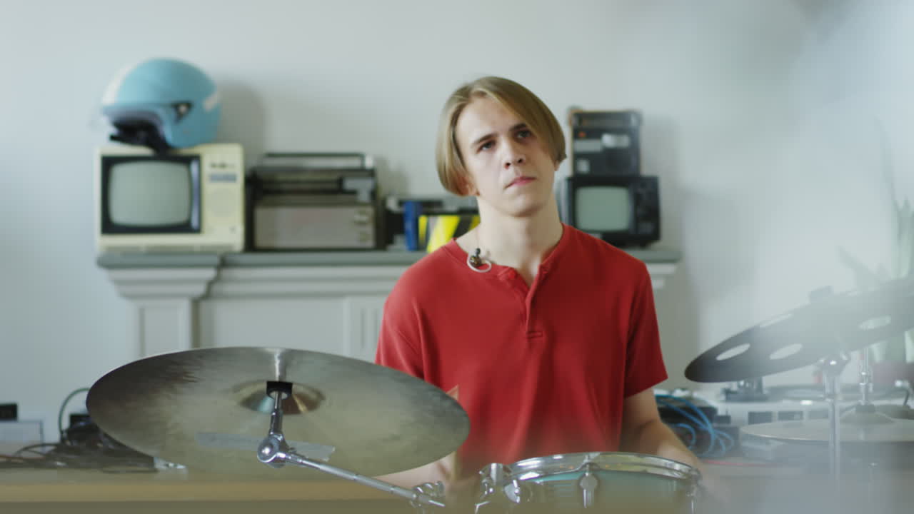 A young man playing drums in a room with vintage electronics