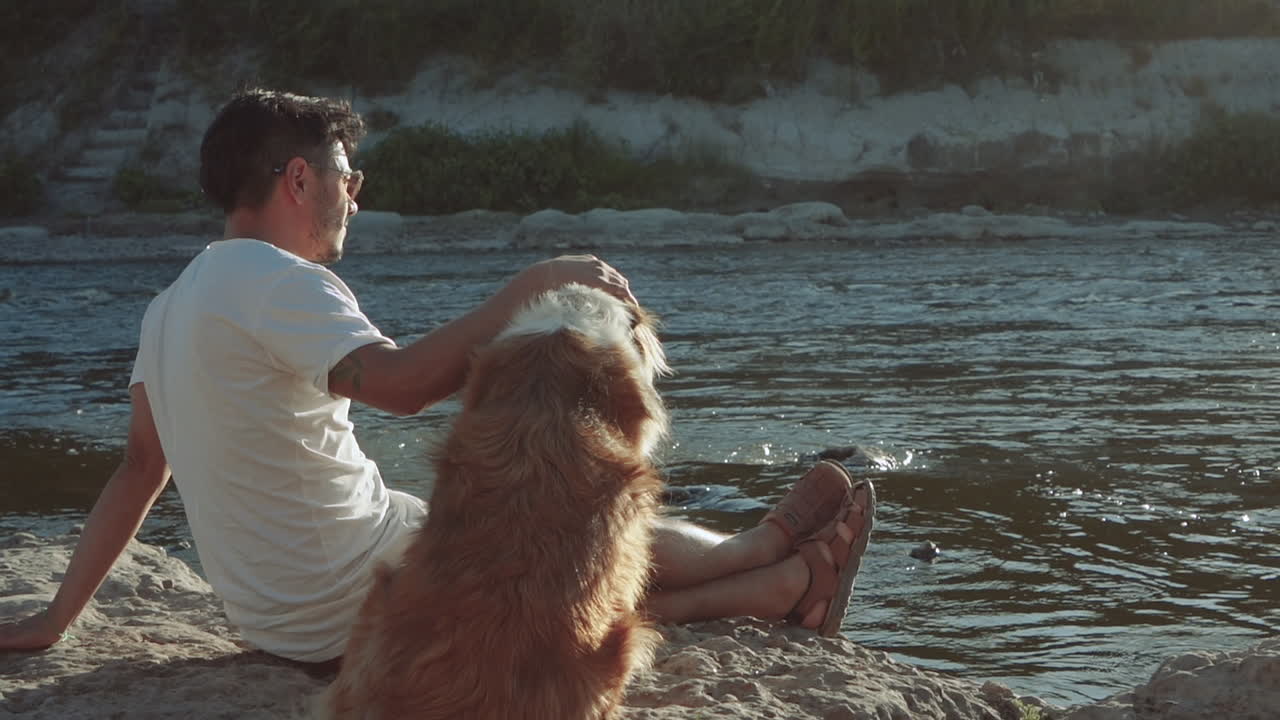 macho y su perro en la orilla del río