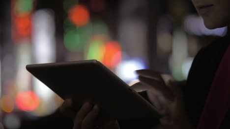 Woman-with-pad-against-colorful-blurred-city-lights-at-night