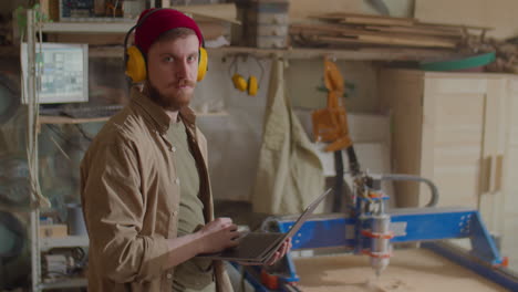 Portrait of Woodworker with Laptop in Workshop