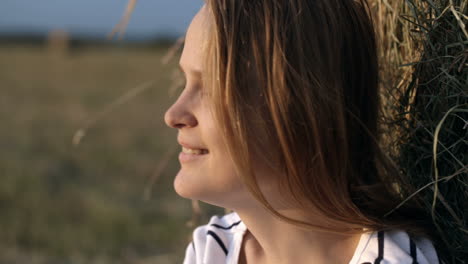 mujer sonriente junto al rollo de heno en el campo