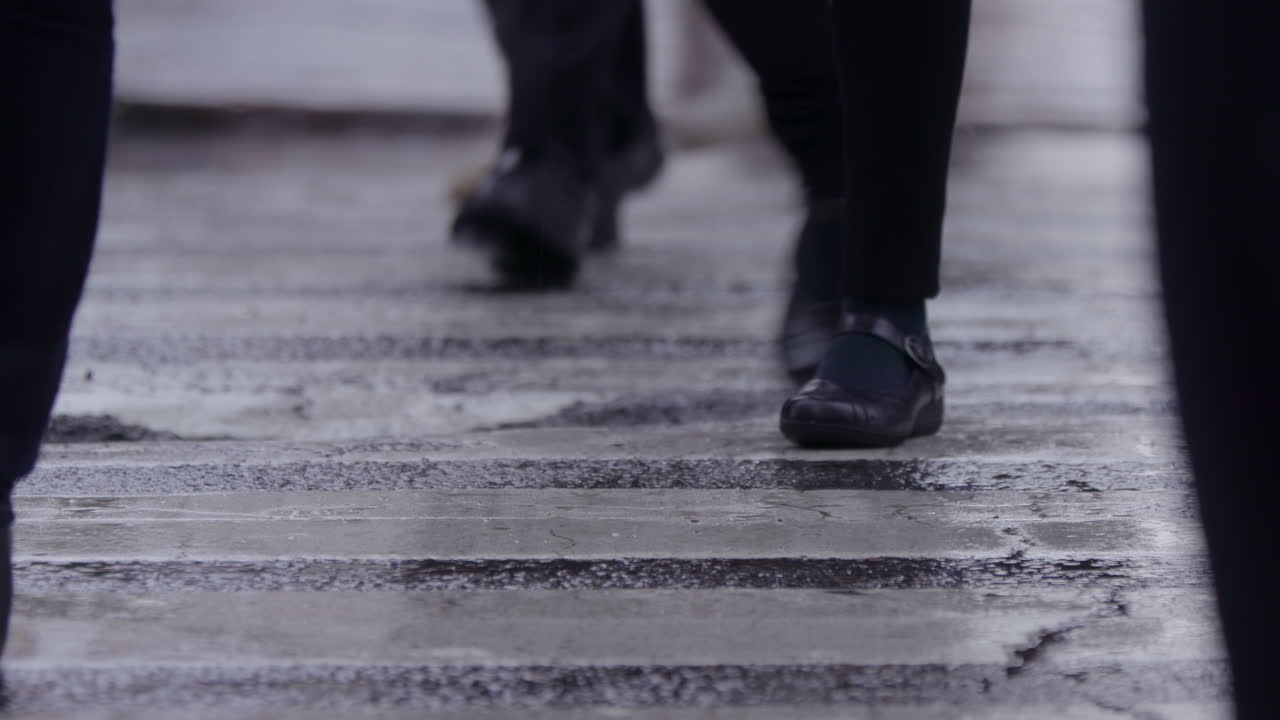 Slow Motion. People's feet, walking across a crosswalk on a wet day. New York City traffic. Rain, Manhattan NYC
