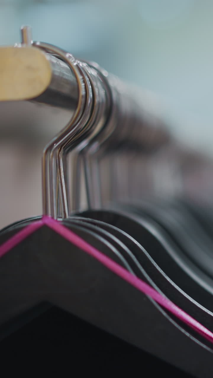 Close-up of clothes on hangers in a clothing store with blurred background, focusing on fabric details and vibrant clothing racks, creating a warm, inviting shopping atmosphere