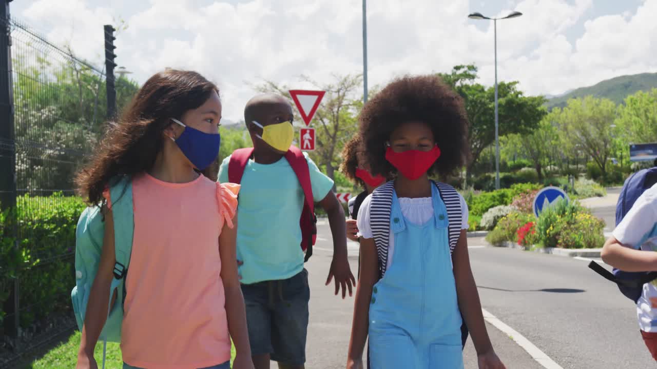 grupo de niños con máscaras faciales caminando por la carretera