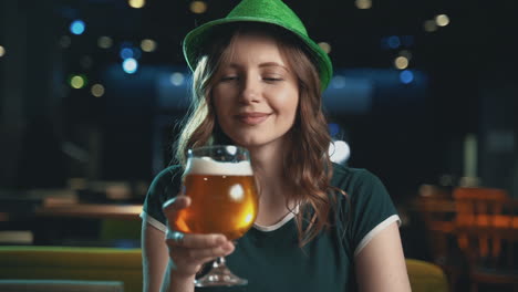 Portrait-Of-Pretty-Young-Woman-Toasting-With-A-Beer-And-Wearing-An-Irish-Green-Hat