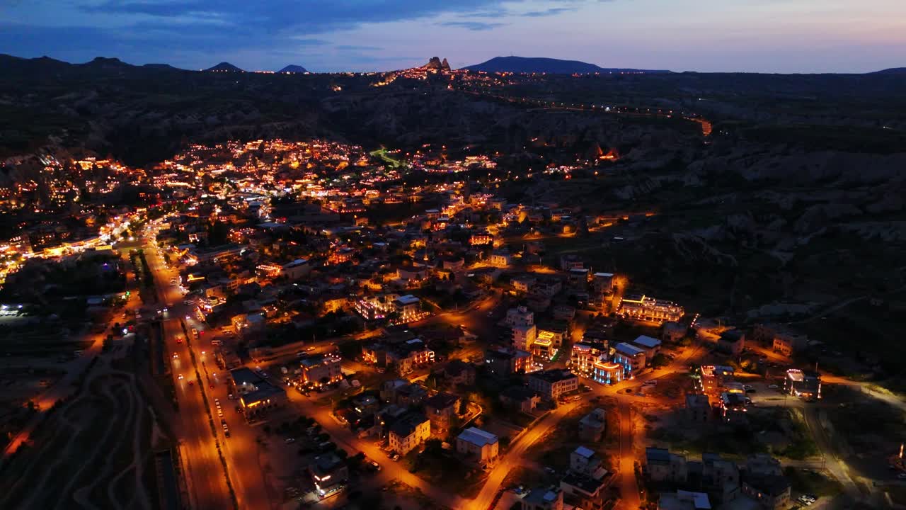 Aerial night view of illuminated town, serene atmosphere, sunset sky