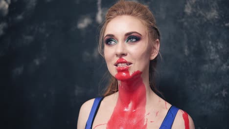 Playful-Ad-Predatory-Young-Woman-Grins-Her-Teeth-With-Red-Paint-On-Her-Neck