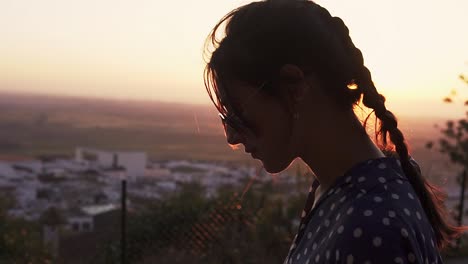 model-fixing-her-hair-with-a-vibrant-sunset-behind-over-the-valley