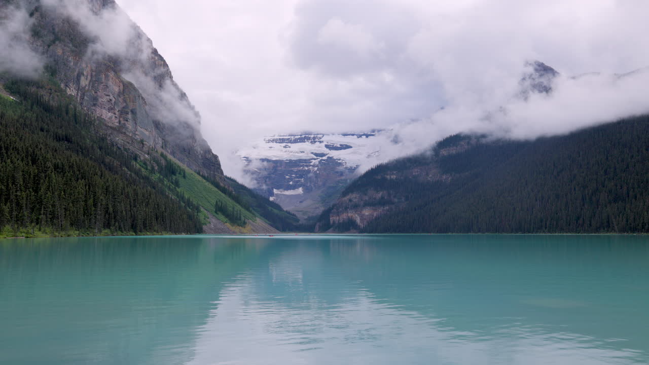 Cloudy day over Lake Louise, turquoise waters reflecting misty Rocky Mountains in Banff National Park